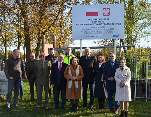 Uczestnicy odbioru inwestycji przy tablicy informacyjnej.