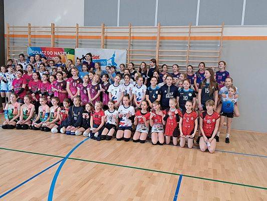 Zdjęcie grupowe uczestników turnieju na hali sportowej.