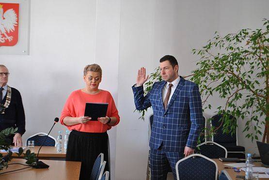 Radny z podniesioną ręką wypowiada słowa przysięgi.