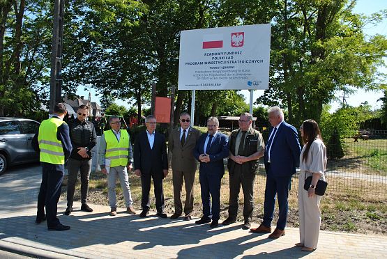 Przedstawiciele instytucji i władz samorządowych przy tablicy informacyjnej dotyczącej inwestycji.