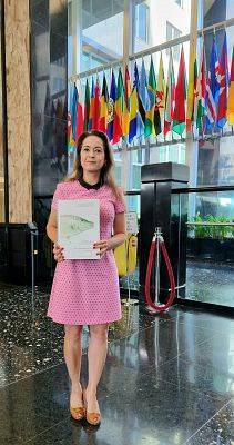 Kobieta stoi z książką w holu budynku.