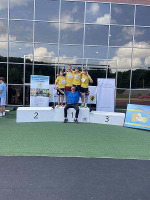 Trener z drużyną sztafety, napodium, pozują do zdjęcia.